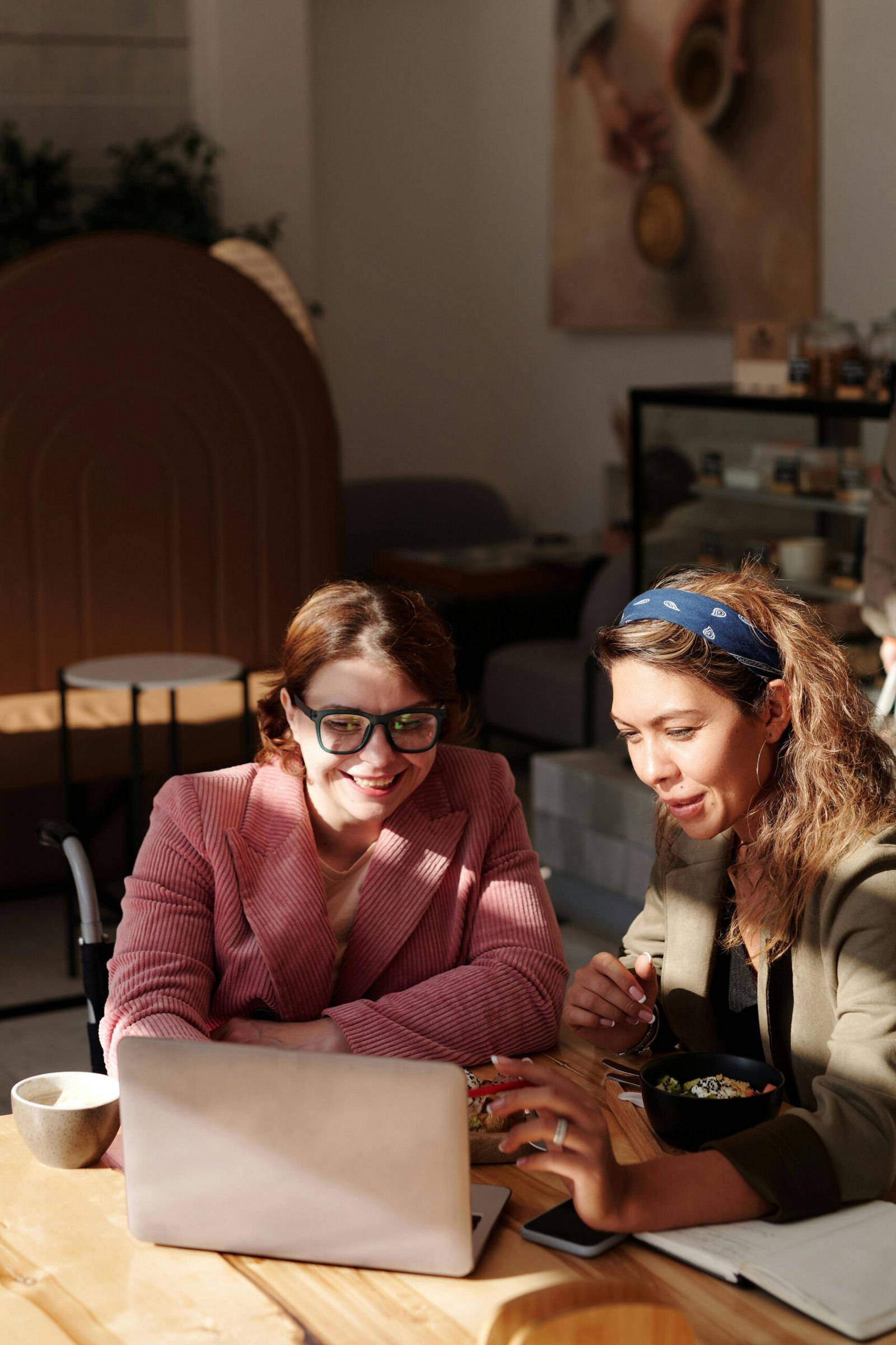 Two women collaborating on a project in a cozy café setting.