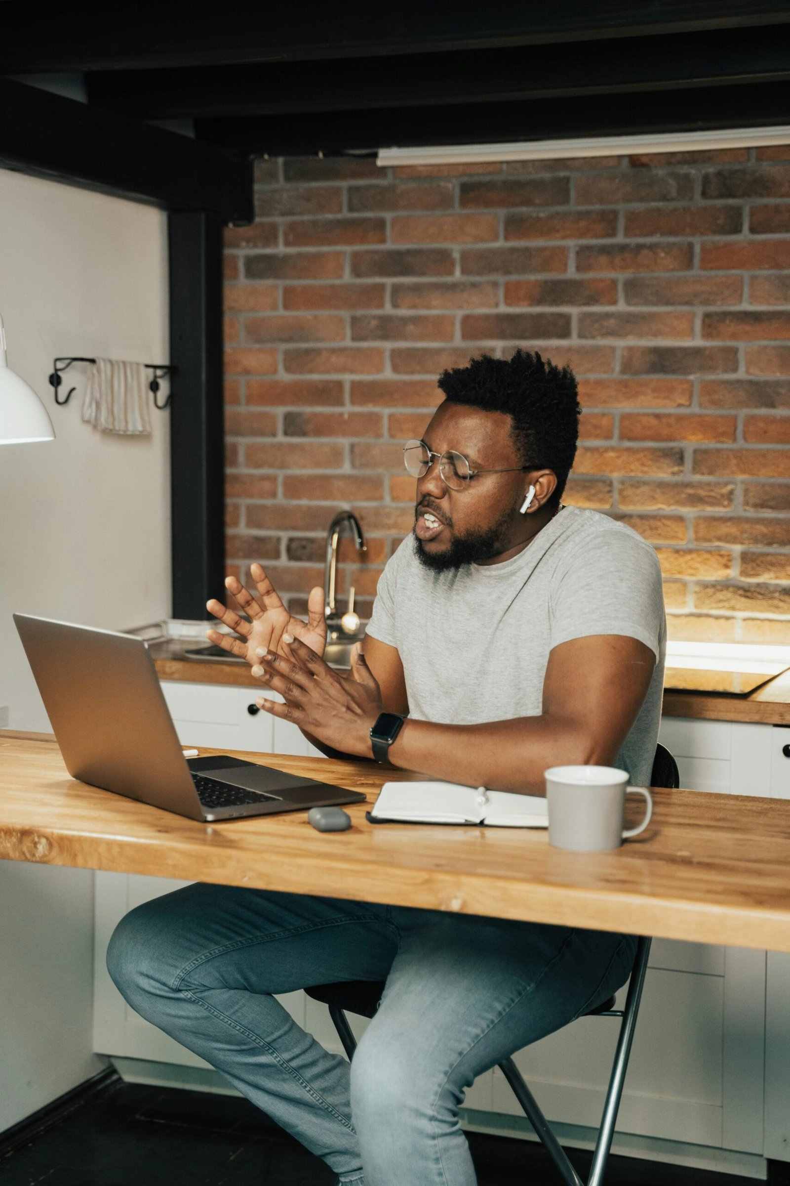 African American man engaged in remote work on a laptop at a home office setting.